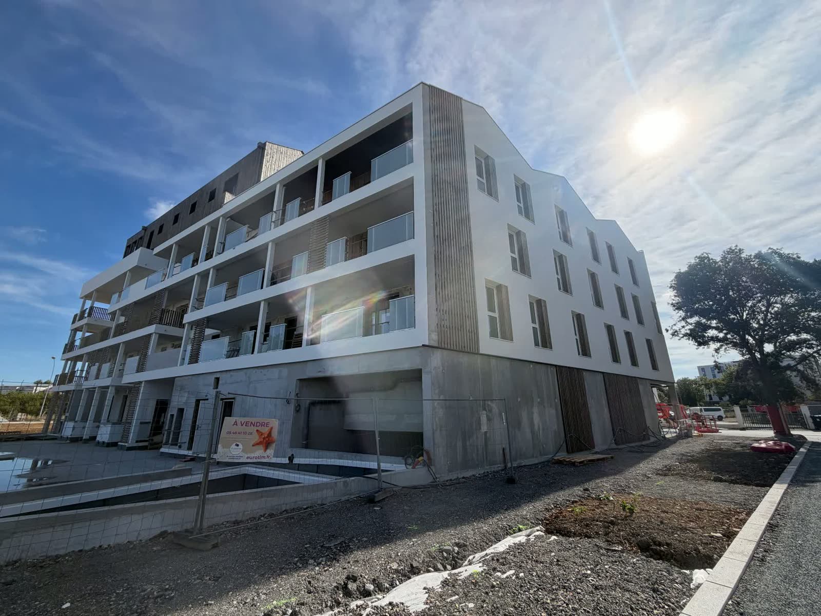 Chantier BABYLONE — Façades blanches et bardages bois en place — dernier niveau en cours de finition